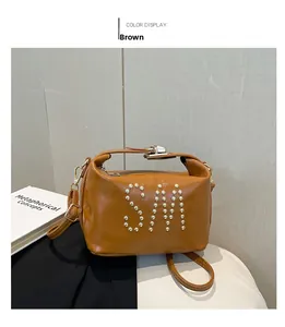 Détail du sac cabas marron avec lettres SM en rivets et fermoir rotatif métallique doré