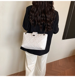Detailed view of white quilted chain shoulder bag with a square metallic turn-lock