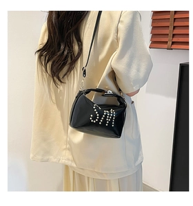 Détail du sac cabas en cuir brillant noir avec logo SM orné de clous blancs arrondis