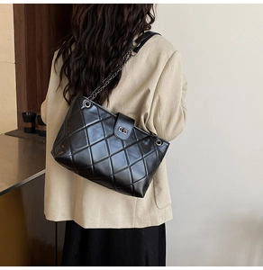 Close-up of black quilted PU leather shoulder bag with chain strap and silver twist lock
