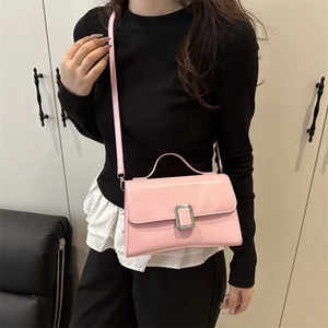 Pink minimalist crossbody flap bag with silver lock buckle and shoulder strap worn by model