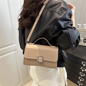 Sac bandoulière rectangulaire beige élégant avec boucle argentée porté par un mannequin