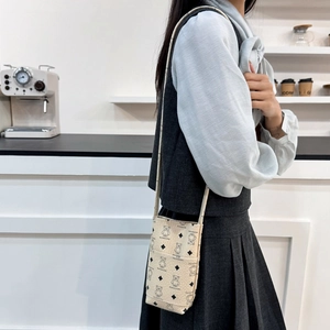 Minimalist beige crossbody phone bag with vintage bear print shown on a model in a cafe