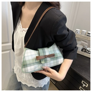 Detail of green and white plaid baguette bag featuring a dark brown ribbon bow detail