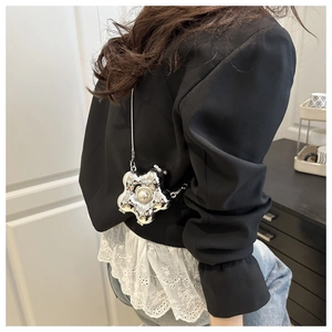 Close-up of a silver flower mini bag with central pearl detail and delicate metal chain