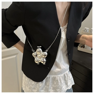 Detail of a silver metallic flower bag with a pearl center and delicate chain strap