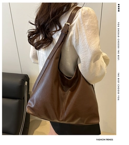 Close-up of the high-quality leather texture and fine stitching on a dark brown tote bag
