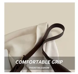 Close-up of the dark brown leather handle and metal buckle on the white bucket bag