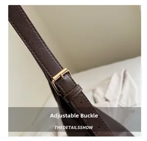 Detail of adjustable shoulder strap with golden buckle on coffee brown leather tote bag