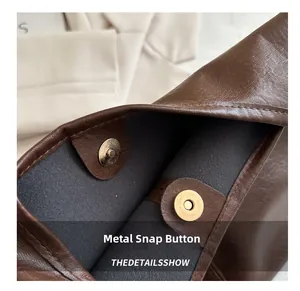 Detailed view of the dark brown leather tote with a bronze magnetic snap closure