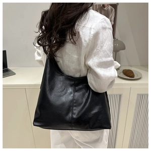 Black large capacity hobo tote bag shown on a model in a minimalist home setting