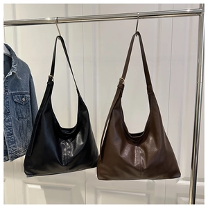 Detail view of large capacity hobo bags in black and brown hanging on a metal rack