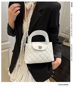 Detailed view of white quilted chain bag worn over the shoulder with black blazer outfit