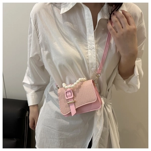 Detail of pink mini bag with woven flap texture and elegant white pearl handle strap