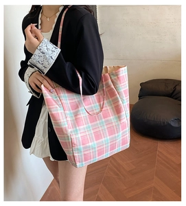Detailed view of large canvas tote bag with pink and blue checkered pattern worn by model