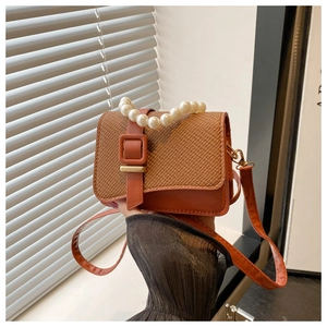 Detail of mini pearl handle crossbody bag with leather and straw patchwork design