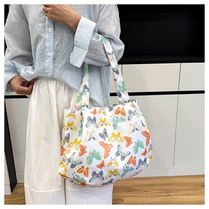 Dettaglio della borsa tote in tela bianca con stampe di farfalle colorate e manici larghi
