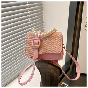 Detailed shot of pink mini crossbody bag featuring pearl handle and woven flap texture