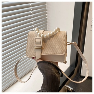 Detail of beige mini square bag with woven texture lid and elegant pearl handle