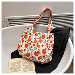 Dettaglio della borsa tote in tela crema con vivaci motivi floreali rossi e viola