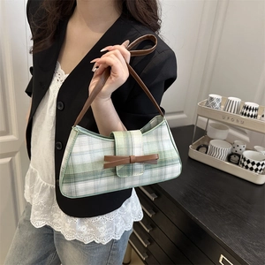 Retro green and white checkered baguette bag with brown bow detail worn as underarm bag