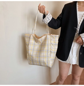 Vue détaillée d'un sac cabas en nylon à carreaux jaunes porté à l'épaule par un mannequin