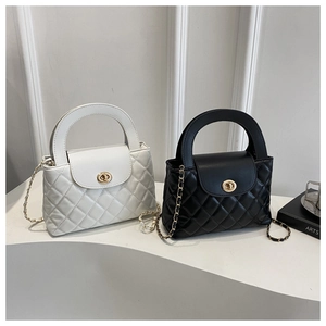 Detail of quilted leather bags with gold rotary lock and elegant chain strap in monochrome