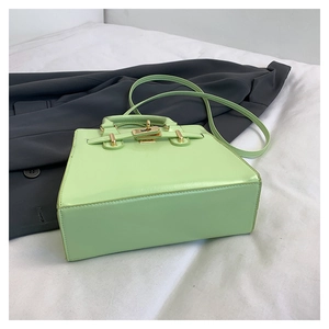 Detail view of light green leather handbag with golden lock and trapezoidal structure