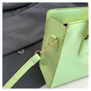 Close-up of lime green leather handbag with gold lobster clasp and detachable strap detail