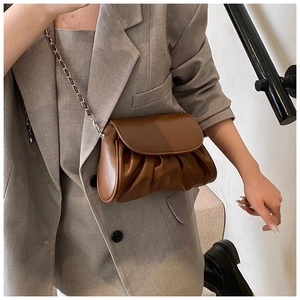 Detail of dark brown ruched cloud bag featuring silver metal chain and leather strap