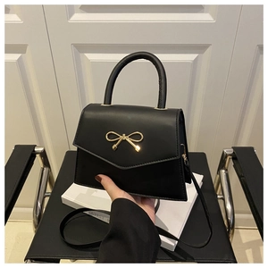 Detail of black crossbody bag with gold metal bow clasp and high-quality matte finish