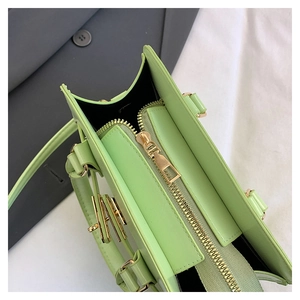 Close-up of mint green handbag featuring golden zipper detail and smooth leather texture