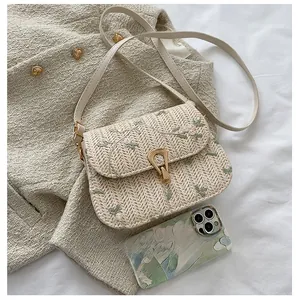 Detail of summer straw bag featuring floral embroidery and gold buckle on tweed fabric