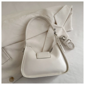 Detail of a creamy beige half-moon underarm bag showing smooth faux leather texture