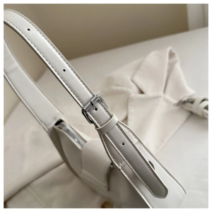 Detail of adjustable shoulder strap with silver buckle on a minimalist white leather bag