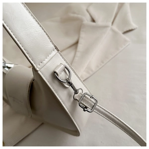 Close-up of polished silver hardware and leather texture on a beige hobo shoulder bag