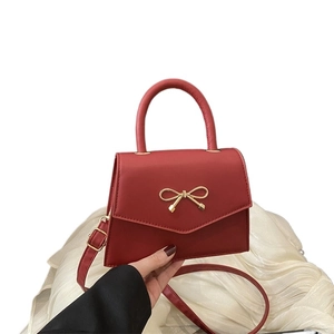 Red pebbled leather mini crossbody bag with golden bow hardware and top handle
