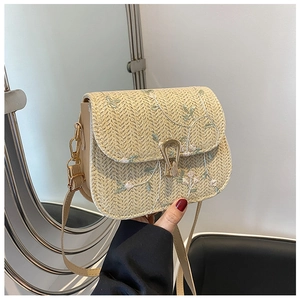 Détail d'un sac en paille tressée avec broderie florale et fermoir doré en fer à cheval