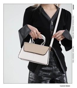 Detail der Crossbody-Tasche aus weißem Leder und khakifarbenem Webstoff mit Silbergriff