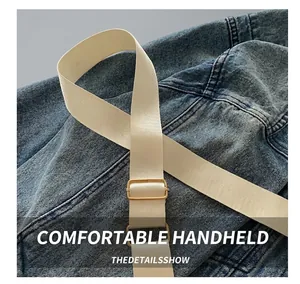 Detailed close-up of adjustable beige fabric strap with gold metal buckle on bag
