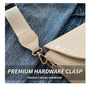 Detailed macro view of beige faux-crocodile embossed leather bag with gold hardware hooks