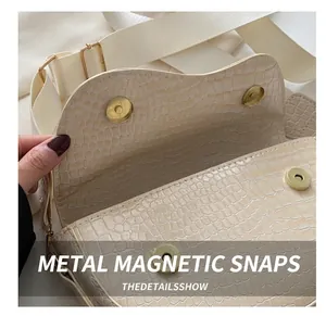 Detail shot of beige faux crocodile leather saddle bag with double magnetic closures