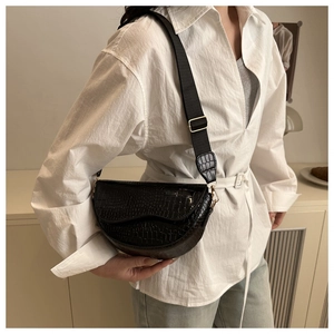 Detail of black crocodile embossed half-moon saddle bag with wide shoulder strap