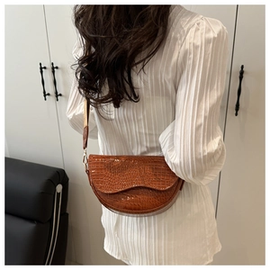 Detail view of brown crocodile pattern half-moon bag with adjustable shoulder strap