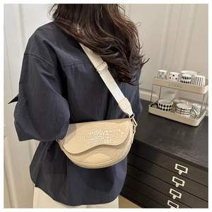 Detail of beige crocodile embossed saddle bag with stylish wide adjustable strap