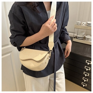 Detailed close-up of beige crocodile pattern semi-circle saddle bag with wide strap