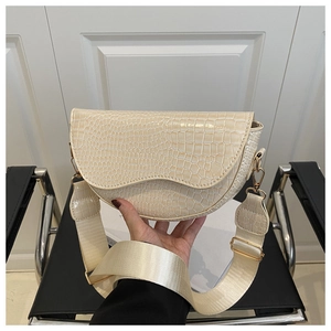 Detail of cream faux crocodile saddle bag with wide woven strap and gold hardware