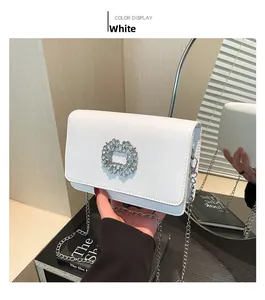 Detail of white PU leather crossbody bag featuring a large sparkling rhinestone buckle