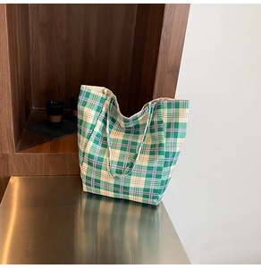Detail of checkered canvas tote bag in green and purple, showcasing textured fabric on a desk