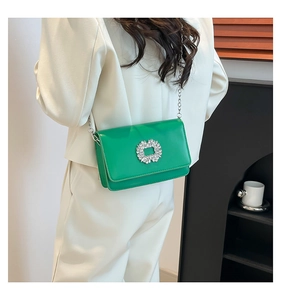 Detail of emerald green crossbody bag with rhinestone buckle on white suit